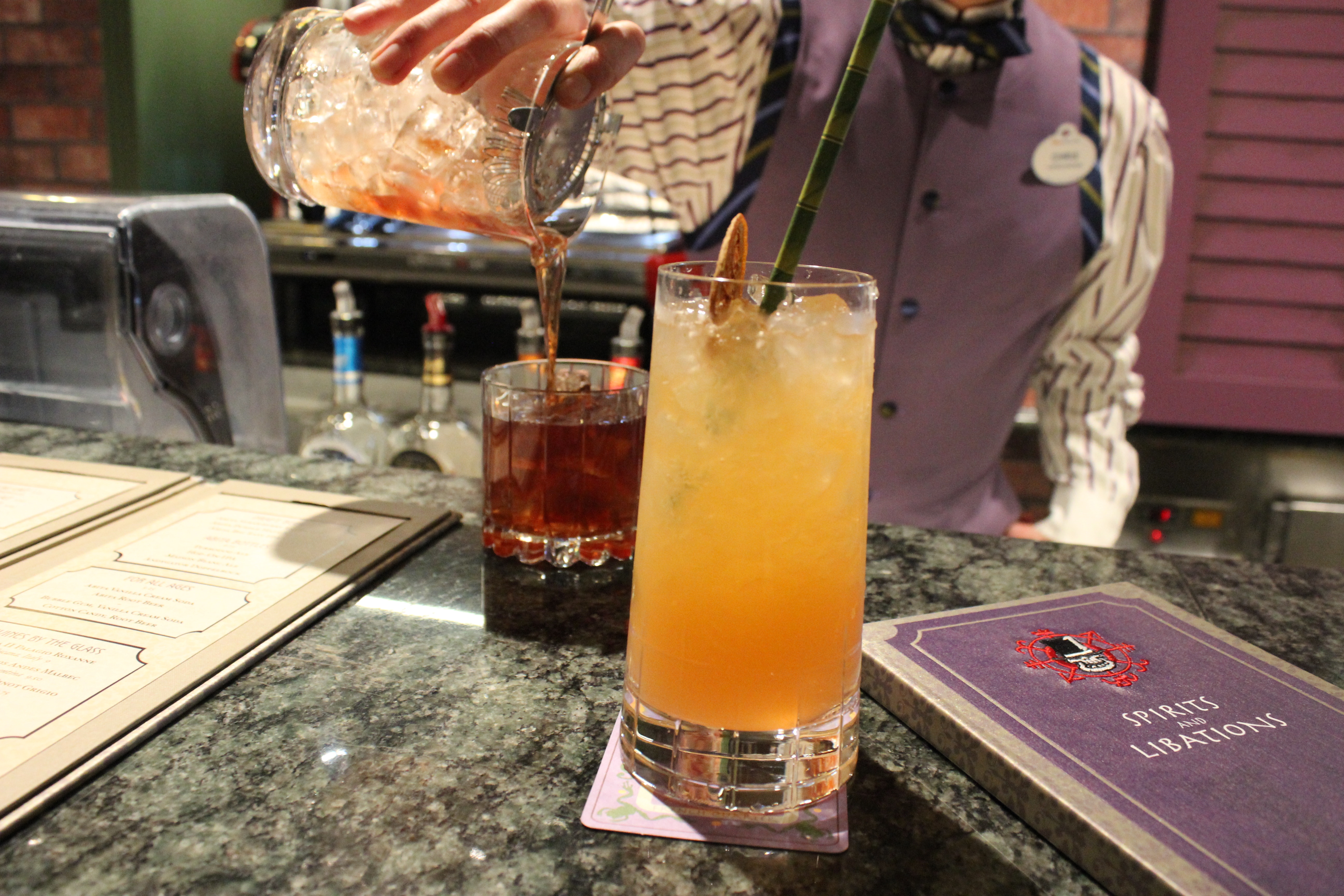 A Lounge bartender finishes a perfect pour on an Old New Orleans Fashioned while a delicious Satsuma Crush sits in front, ready to be enjoyed.